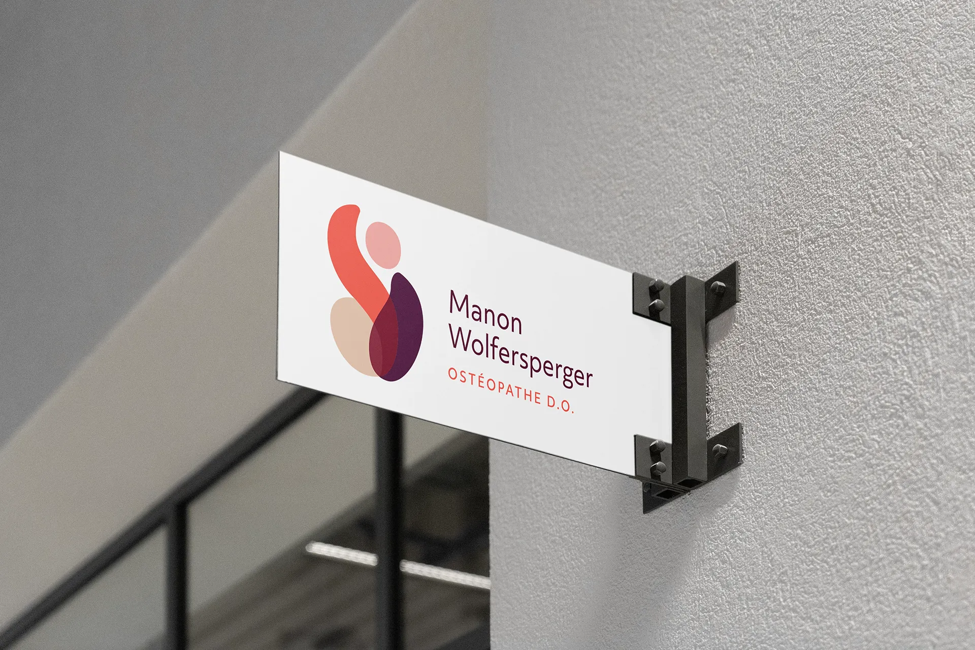 Plaque de cabinet Manon Wolfersperger Ostéopathe D.O. avec logo et identité visuelle appliqués sur une enseigne murale.